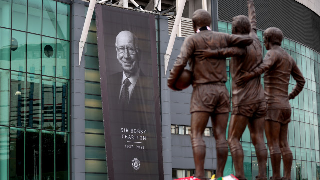 A tribute to Sir Bobby Charlton hangs outside the Old Trafford stadium with the United Trinity statue of former players George Best, Denis Law and Bobby Charlton in foreground, Manchester, Britain, 24 October 2023